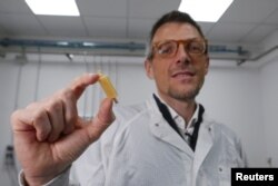 Senior researcher Mario Caironi shows a rechargeable edible battery made from food in Milan