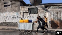 Youths push a cart loaded with jerrycans to be filled with water along a street in Rafah in the southern Gaza Strip on October 31, 2023 amid ongoing battles between Israel and the Palestinian Hamas movement. 