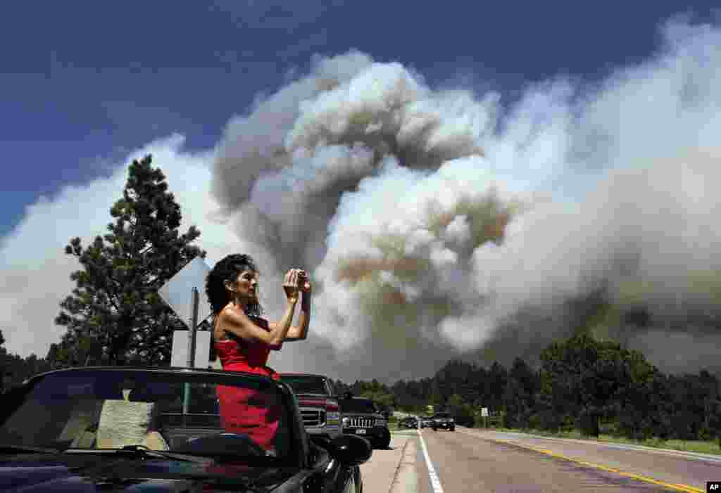 Colorado Springs resident Yolette Baca takes a photo of the wildfire in the Black Forest area north of Colorado Springs, Colorado, June 12, 2013. 