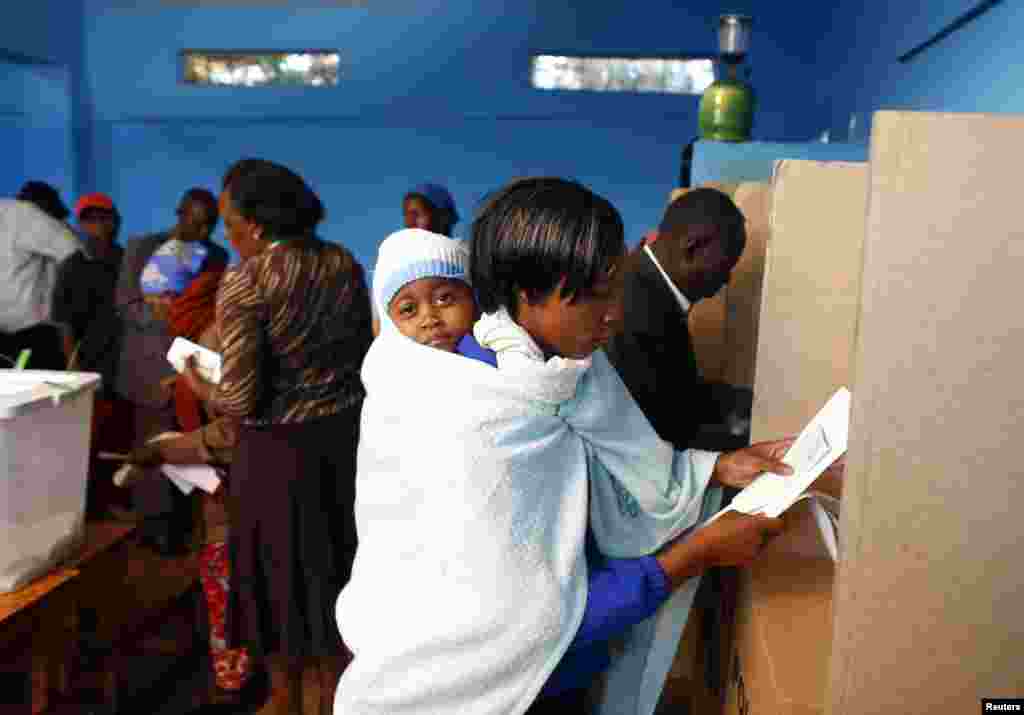 Mwanamke akiwa na mtoto wake anapiga kura ndani ya kituo cha Gatundu March 4, 2013. 
