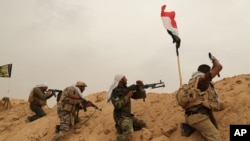 FILE - Fighters from Badr Brigades Shiite militia clash with Islamic State group militants at the front line on the outskirts of Fallujah, Anbar province, Iraq, June 1, 2015. 