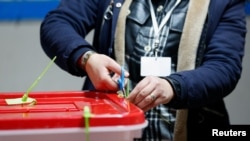 A member of the election committee opens a ballot box at a polling station during the second round of the parliamentary election in Tunis, Tunisia January 29, 2023. 