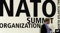 A man walks by signage at the NATO summit venue in Lisbon, Portugal, 18, Nov. 2010. Heads of State of NATO member countries gather for a two day summit beginning Friday.