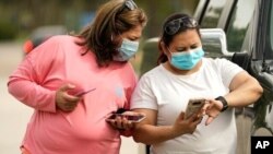 دو زن در شهر هیوستون ایالت تگزاس به تلفن‌های هوشمندشان نگاه می‌کنند