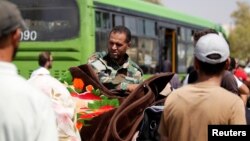 FILE - A Syrian army soldier inspects people's belongings before their evacuation from Damascus suburb of Mouadamiya, under an agreement between rebels and Syria's army, Sept. 8, 2016. 