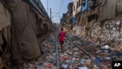 FILE - A man walks on a railway track littered with plastic and other waste materials on Earth Day in Mumbai, India, April 22, 2024. (AP Photo/Rafiq Maqbool, File)