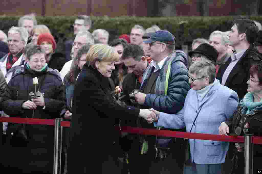 German Chancellor Angela Merkel shakes hands with people prior to a ceremony at the Berlin Wall memorial site at Bernauer Strasse in Berlin, Germany. 