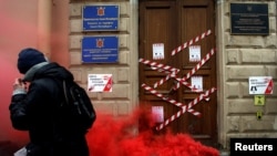 FILE - A protester walks past a defaced entrance of Russian government media watchdog Roskomnadzor's office, in central St. Petersburg, March 10, 2019.