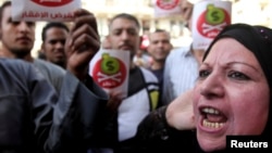 Egyptian protesters hold placards with the Arabic inscription reading ‘danger’ and shout slogans as they demonstrate against the International Monetary Fund (IMF) delegation visit, in front of the General-Prosecutor's office in Cairo Apr. 3, 2013.