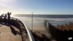 People look out toward where border structure separates San Diego, right, from Tijuana, Mexico, left, Jan. 25, 2017. President Donald Trump moved aggressively to tighten the nation's immigration controls Wednesday, signing executive actions to jump-start 