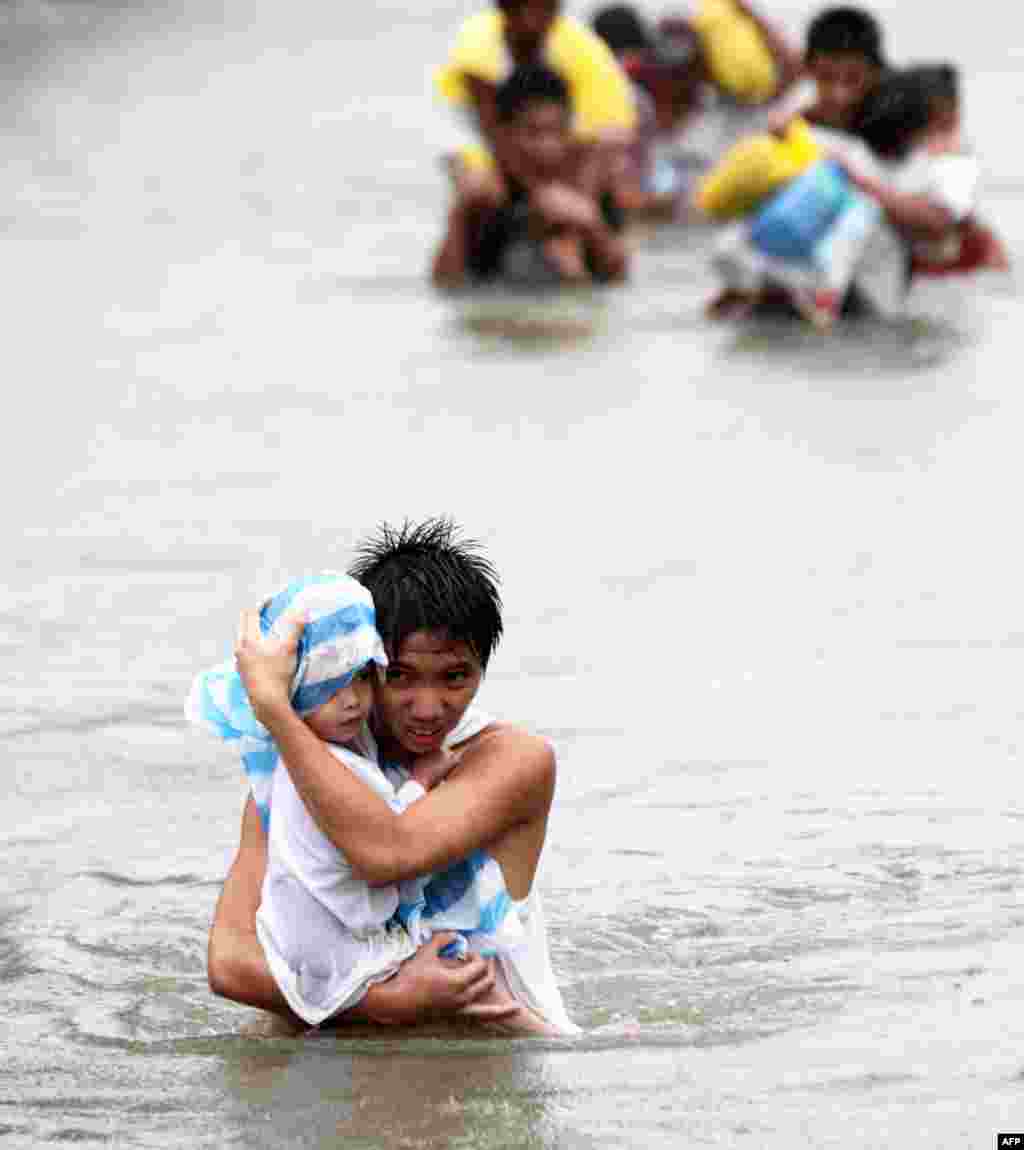 27 tháng 9: Dân chúng Philippines ở thành phố Malabon phía bắc Manila đi trên con đường ngập nước sau bão Nesat. (REUTERS/Stringer)