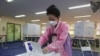 A woman wearing a face mask to help protect against the spread of the new coronavirus casts a vote for the parliamentary elections at a polling station in Seoul, South Korea, April 15, 2020. 