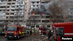 Petugas pemadam kebakaran bekerja di sebelah bangunan tempat tinggal yang terbakar yang rusak berat akibat serangan rudal Rusia di Kyiv, Ukraina 2 Januari 2024. (Foto: REUTERS/Danylo Antoniuk)