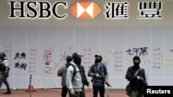 FILE - Armed undercover police officers guard a vandalized HSBC bank branch in Wan Chai during demonstrations on the New Year's Day in Hong Kong, Jan. 1, 2020. 