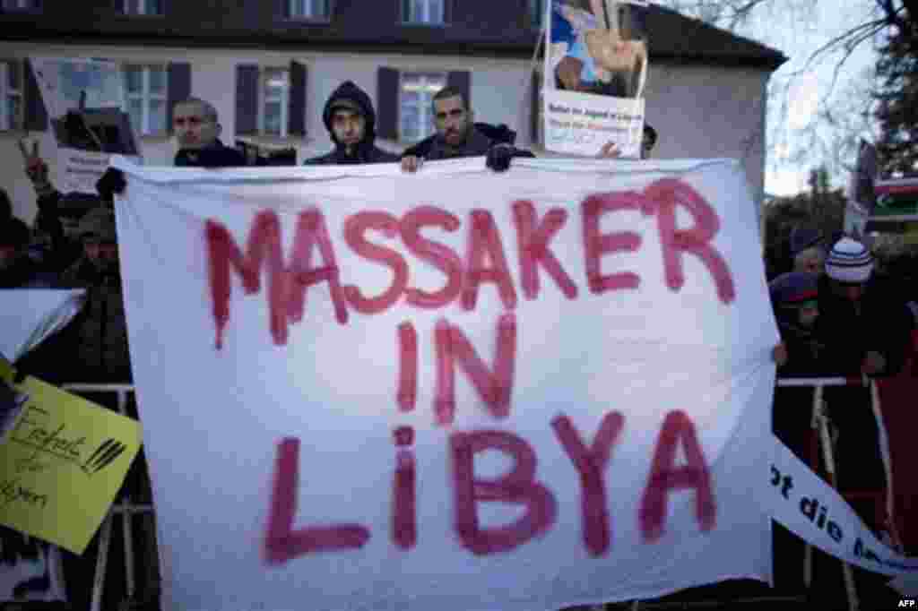 Demonstrators hold posters as they call for the ouster of Libyan leader Moammar Gadhafi near the Libyan embassy in Berlin on Monday, Feb. 21, 2011. The posters read from left: Freedom For Libya', 'Massacre in Libya' and 'Save the youth in Libya - Stopp th