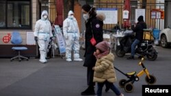 Guards in protective suits keep watch at the gate to a residential compound as coronavirus disease (COVID-19) outbreaks continue in Beijing, Dec. 7, 2022. 