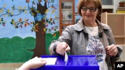 A woman casts her ballot at the polling station in Montenegro's capital Podgorica, Sunday, April 15, 2018. 