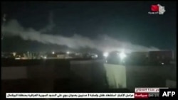 This image grab taken from a broadcast by Syria TV on June 28, 2021, shows smoke billowing from a facility used by Iran-backed groups following U.S. airstrikes on the Syrian-Iraqi border. 