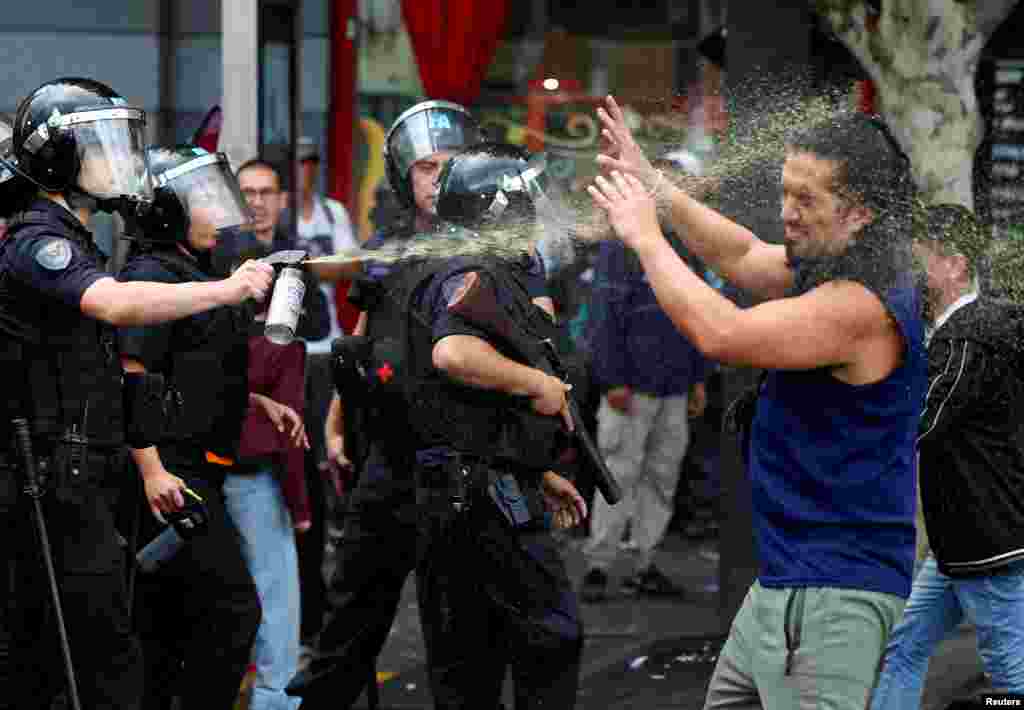 A police officer uses a crowd control spray on a demonstrator as football fans join the weekly protest of retirees against Argentinian President Javier Milei's adjustment policies, in Buenos Aires, March 12, 2025.