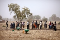FILE - People work in a dry field near Diapaga, 300 kms northeast of Ouagadougou, Burkina Faso, March 21, 2012.