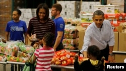 Presiden AS Barack Obama dan ibu negara Michelle Obama menyerahkan bantuan makanan untuk Thanksgiving kepada warga kurang mampu di Washington DC (27/11). 