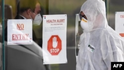 ကိုရိုနာဗိုင်းရပ်စ် ကူးစက်မှု ကာကွယ်နိုင်ရေး ဝတ်စုံပြည့် ဝတ်ဆင်ထားတဲ့ သြစတြေးလျနိုင်ငံ မဲလ်ဘုန်းမြို့က ကျန်းမာရေးဝန်ထမ်းတဦး။ (ဇူလိုင် ၃၀၊ ၂၀၂၀)