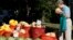FILE - A shopper inspects fresh-picked melons and other summer garden vegetables are displayed for sale at a farmers market in Falls Church, Va., Aug. 8, 2015.