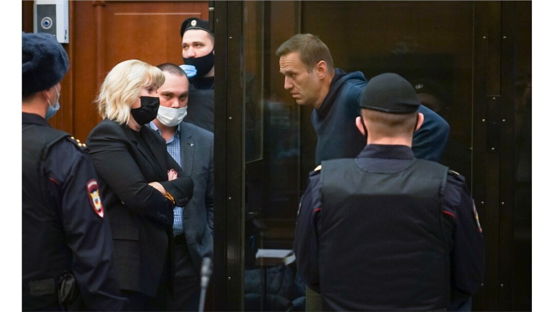FILE - In this handout photo provided by Moscow City Court, Russian opposition leader Alexey Navalny talks to his lawyers during a hearing, in Moscow, Russia, Feb. 2, 2021.