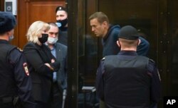 FILE - In this handout photo provided by Moscow City Court, Russian opposition leader Alexey Navalny talks to his lawyers during a hearing, in Moscow, Russia, Feb. 2, 2021.