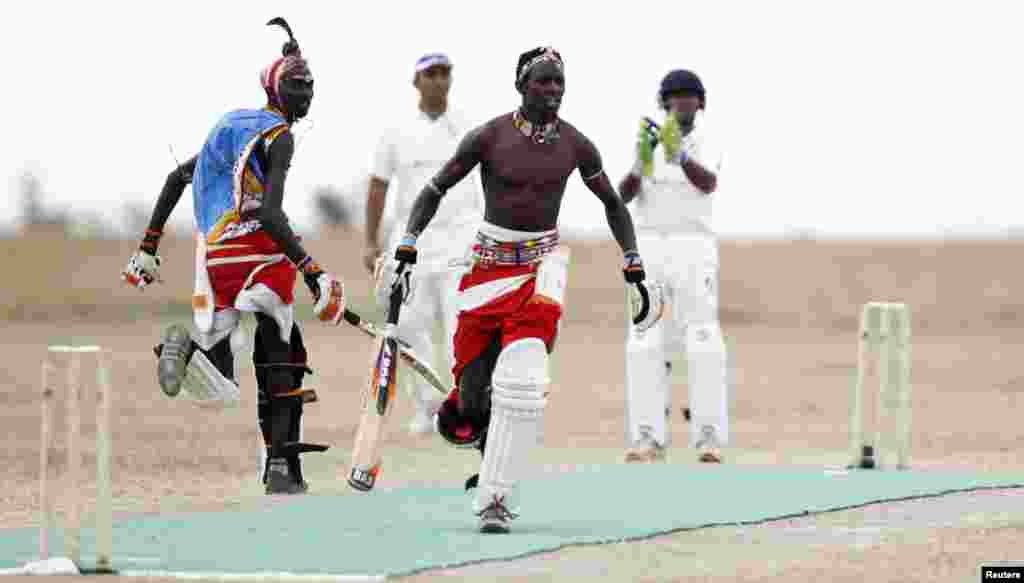 Sonyanga Olengais (C), captain of the Maasai Cricket Warriors, and his teammate Thomas Takare run between the wickets during their Twenty20 cricket match against the Ambassadors of Cricket from India, in Ol Pejeta conservancy in Laikipia National Park, Kenya.