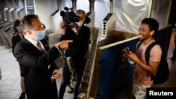 Gubernur New York Andrew Cuomo menyapa para pengguna subway di Manhattan pada hari pertama pembukaan kembali kegiatan di Kota New York di tengah pandemi virus corona, 8 Juni 2020.