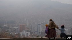 Una mujer acompaña a su hija a la escuela en medio del humo de los incendios forestales en La Paz, Bolivia, el lunes 9 de septiembre de 2024. 