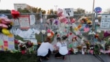 FILE - People light candles at a makeshift memorial outside Marjory Stoneman Douglas High School, where 17 students and faculty were killed in a mass shooting days earlier in Parkland, Fla.