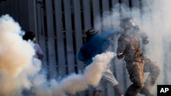 反政府抗议者在曼谷一座体育场与防暴警察冲突。图为抗议者把警察发射的催泪瓦斯罐投掷回去。