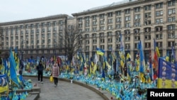 Orang-orang mengunjungi tugu peringatan darurat untuk mengenang tentara Ukraina yang gugur, di tengah serangan Rusia terhadap Ukraina, di Lapangan Kemerdekaan di Kyiv, Ukraina, 14 Februari 2025. (Foto: REUTERS/Valentyn Ogirenko)