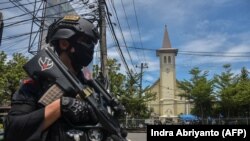 Polisi berjaga di luar gereja pasca ledakan di Makassar pada 28 Maret 2021. (Foto: AFP/Indra Abriyanto)