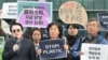 An activist stands with other protesters as he holds a sign that reads “Stop Plastic” in the grounds outside BEXCO, the venue for the fifth session of the UN Intergovernmental Negotiating Committee on Plastic Pollution (INC-5), in Busan on November 25, 20