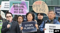 An activist stands with other protesters as he holds a sign that reads “Stop Plastic” in the grounds outside BEXCO, the venue for the fifth session of the UN Intergovernmental Negotiating Committee on Plastic Pollution (INC-5), in Busan on November 25, 20