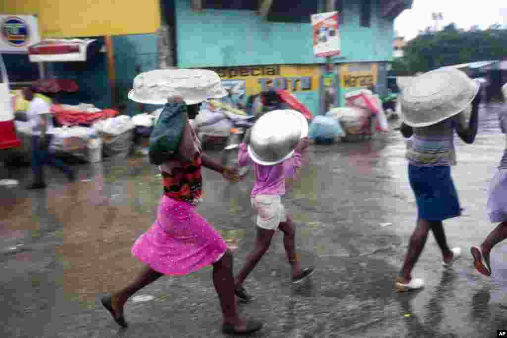 Women cover their heads with pans as they walk in a light rain brought by Hurricane Matthew in Port-au-Prince, Haiti, Oct. 4, 2016. Hurricane Matthew roared into the southwestern coast of Haiti, threatening a largely rural corner of the impoverished country with devastating storm conditions as it headed north toward Cuba and the eastern coast of Florida.