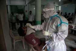 A health worker takes a nasal swab samples to test for COVID-19 in Gauhati, India, Aug. 7, 2020.