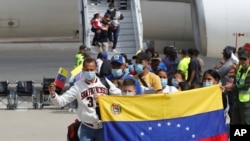 Una familia venezolana posa con la bandera de su país al aterrizar en el aeropuerto internacional Simón Bolívar, de Maiquetía, La Guaira, el 24 de febrero de 2025. AP/Cristian Hernández