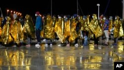 Para migran turun di pelabuhan Roccella Jonica, wilayah Calabria, Italia selatan, Minggu dini hari, 14 November 2021. (AP/Alessandra Tarantino)