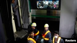 首尔一地铁站内工人在检查事故，对面车厢内乘客正在观望。2014年5月2日拍摄