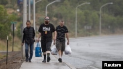 Residents Elaine Shelby, Josh Mortensen and John Lynn walk home with groceries during a flash flood warning in the aftermath of the Salt fire and South Fork fire in Ruidoso Downs, New Mexico, June 21, 2024.