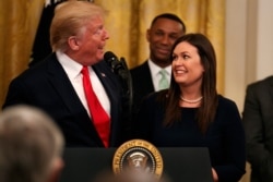 President Donald Trump welcomes White House press secretary Sarah Sanders to the stage as he pauses from a speech to publicly thank the outgoing press secretary, in the East Room of the White House, June 13, 2019, in Washington.