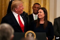 President Donald Trump welcomes White House press secretary Sarah Sanders to the stage as he pauses from a speech to publicly thank the outgoing press secretary, in the East Room of the White House, June 13, 2019, in Washington.