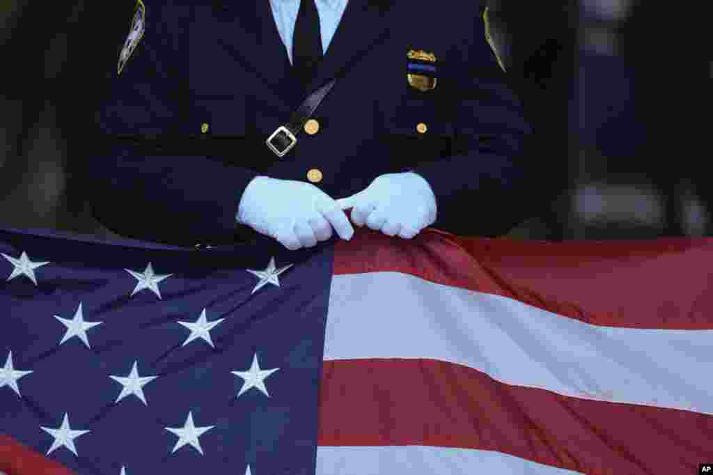 A New Jersey police officer holds an American fag before the start of the ceremony at the 9/11 Memorial on the 23rd anniversary of the terror attacks, in New York, Sept. 11, 2024.