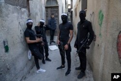 FILE - Palestinian gunmen pose for a photo in an alley during preparations for a military parade of the Balata Battalion, an armed Palestinian network against the Israeli occupation, in the West Bank refugee camp of Balata, near Nablus, November 4, 2022.