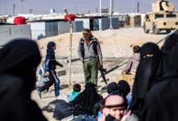 FILE - A member of Kurdish internal security stands guard at the Kurdish-run al-Hol camp, in northeastern Syria, Jan. 28, 2021.