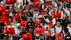 Manifestantes sostienen carteles en una marcha contra las enmiendas propuestas a una ley de extradiciones en Hong Kong, el domingo 9 de junio de 2019. (AP Foto/Kin Cheung)